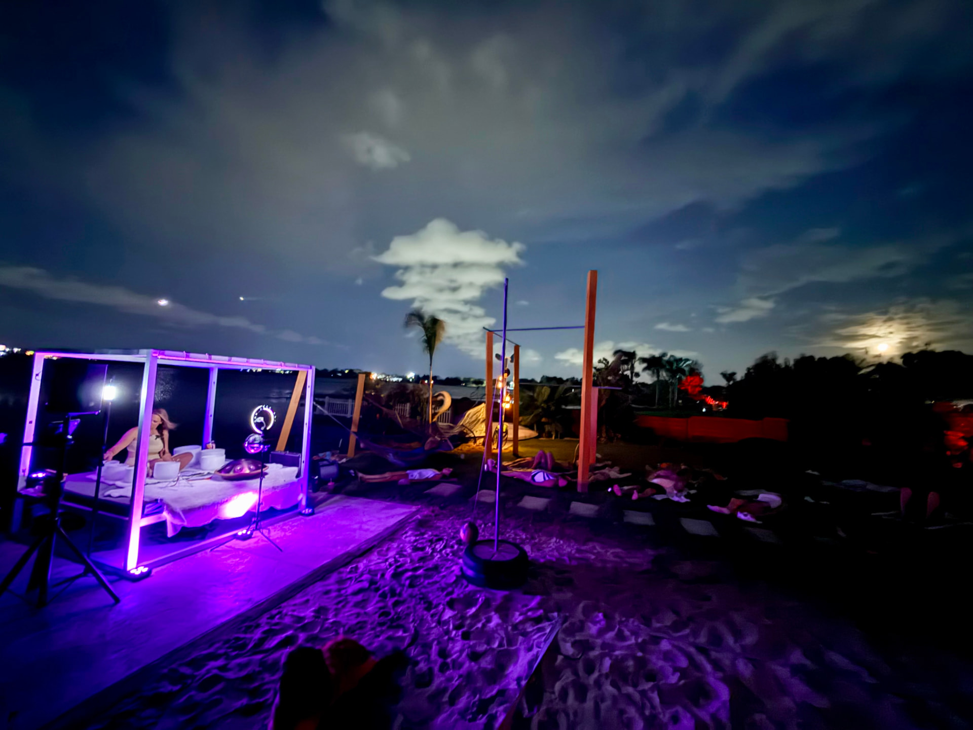 Guests resting on the sand during a moonlit beachside sound bath